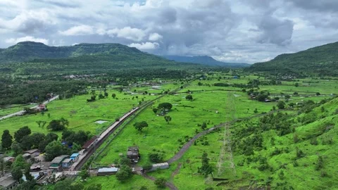 Drone shot of a train passing through lush green hills in Lonavala, Maharashtra Stock Footage 311790526