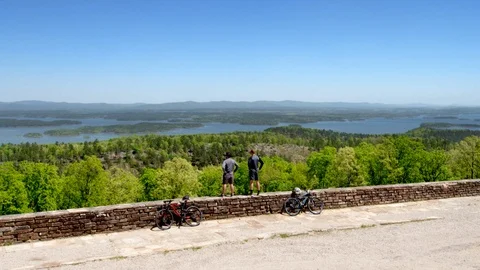 Drone Shot of Two Bikers Overlooking Beautiful Lake, Hands on Hips Stock Footage 95944830