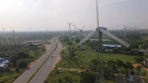 Drone shot of a two-lane busy roadway dividing huge farm of wind turbines Stock Footage 154367705