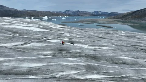 Drone shot of two people walking on Greenland inland ice sheet Stock Footage 332380249