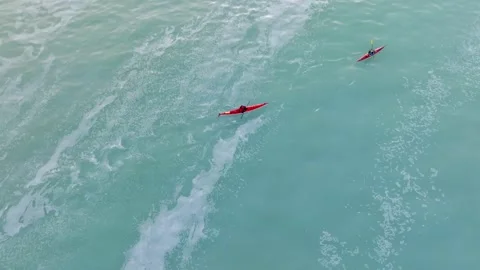 Drone shot of Two red kayaks paddle through a herring spawn on Vancouver Island Stock Footage 345174518