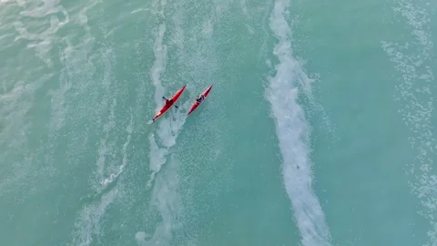Drone shot of Two red kayaks paddle through a herring spawn on Vancouver Island Video stock 345174631