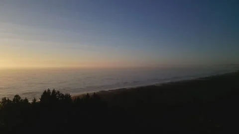 Drone shot of vast ocean descends behind trees at sunset Stock Footage 249029077