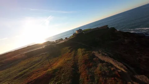 Drone shot from water level, following waves to cliffside at golden hour Stock Footage 344557765