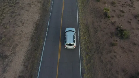 Drone shot of a white Jeep driving down a desert road Stock Footage 128656971