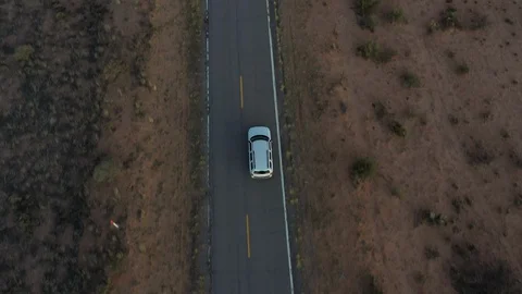 Drone shot of a white Jeep driving down a desert road Stock Footage 128658366