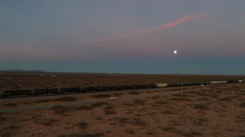 Drone shot of a white Jeep driving down a desert road with a train in background Stock Footage 128658938