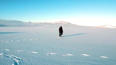 Drone shot of a young man walking through the snow in the cold winter, Iceland. Vídeo Stock 281469862