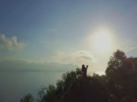 Drone Shows Girl Relaxing on Cliff under Morning Sun Stock Footage