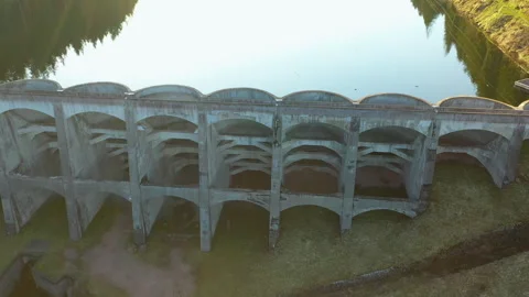 Drone side flyby along concrete dam with reflection, cinematic aerial tracking s Video stock 333069866