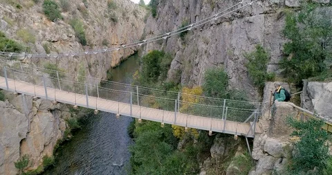 Drone in side motion of suspension bridge and senior hiker crossing Stock Footage 124389067
