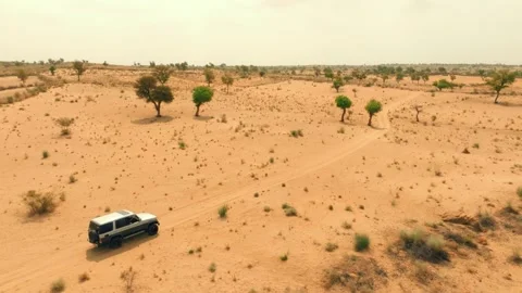 Drone side view of a lone 4x4 driving along a sandy trail through the Thar Stock Footage 345846549