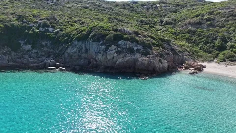 Drone Sideways Flight Along Turquoise Beach with Towering Green Rocky Mo Vídeo Stock 334341925