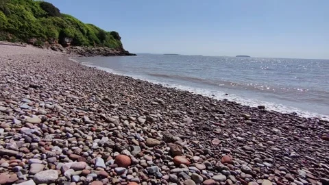 Drone skims over stony beach in sunshine V2 Stock Footage 309187941