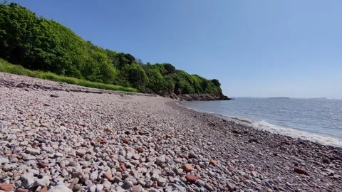 Drone skims over stony beach in sunshine Stock Footage 309188382