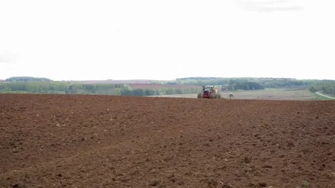 Drone sliding shot of a farmer in tractor seeding, sowing agricultural Stock Footage 132583393