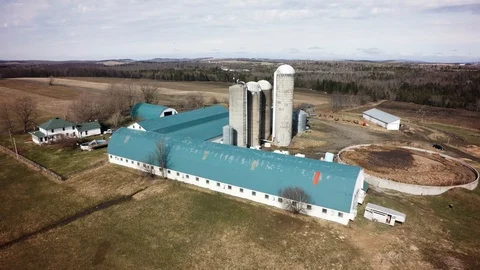 Drone slow flyover quebec dairy farm silos in spring Stock Footage 93363099