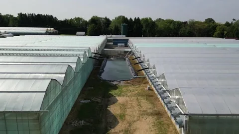 Drone - Slow Low Cruise Between Greenhouses with Water Supply Stock Footage 314227551