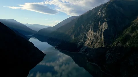 Drone slow pan over calm lake with mountains and beams of light Stock Footage 241172552
