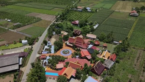Drone slow pull back over a colorful Buddhist temple complex in rural fields 스톡 동영상 335806063