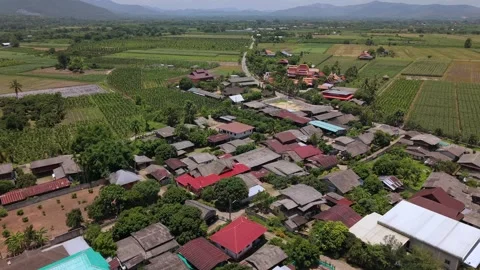 Drone slow pull back over a rural village toward vast agricultural fields Stock Footage 335806159