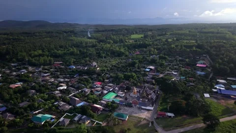 Drone slow pull back revealing a rural village and golden temple complex Stock Footage 335792664