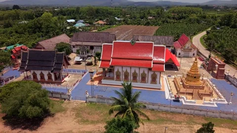 Drone slow pull back revealing a golden chedi and Buddhist temple compound Stock Footage 335806073