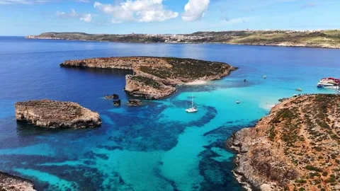 Drone slow pullback over Blue Lagoon shallow basin and limestone islets Comino Stock Footage 333991461