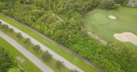 Drone slow reveal of empty road in florida trees and golf course Stock Footage 94840236