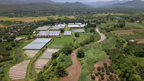 Drone slow tracking shot over valley greenhouses, winding river and mountains Stock Footage 335806101