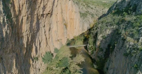 Drone is slowly approaching inside vertical wall ravine and a suspension bridge Stock Footage 124387995