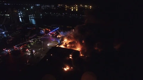 Drone slowly approaching large fire at night burning through roof of structure Video stock 92644024
