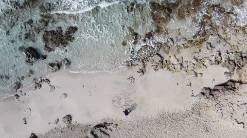 Drone Slowly Ascending Away From Men Drawing On The Beach (sand) Stock Footage 153247447