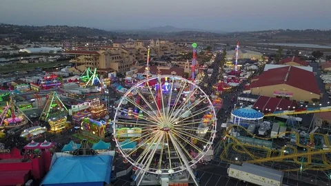 Drone slowly ascends over fair carnival rides and midway amusements in late day 库存影片 98268429