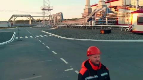 A drone slowly flies over a worker in an orange work helmet at an oil and gas Stock Footage 155767874