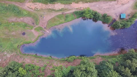 Drone slowly flies to small blue lake on whose coasts people rest in summer Stock Footage 137650268