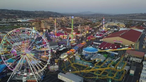 Drone slowly fly over fair carnival rides and midway amusements in late day Stock Footage 98268372