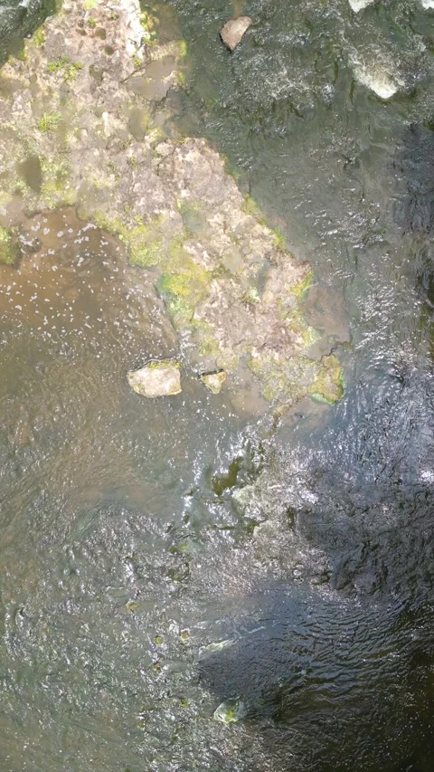 Drone slowly flying down river over a small waterfall Video stock 246717549