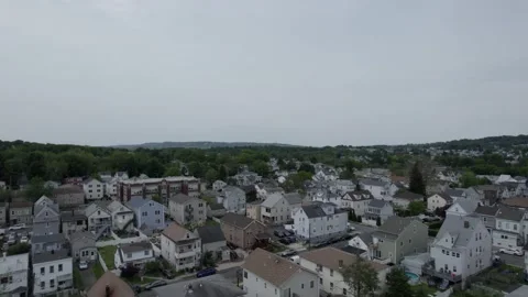Drone slowly hovering over town with trees on horizon 스톡 동영상 160072015