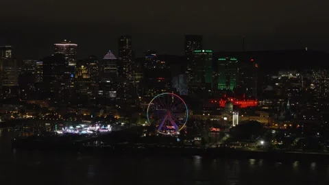 Drone slowly pulling back from Montreal downtown skyline and lit Ferris wheel Stock Footage 347354040
