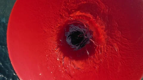 The drone slowly rises above a round red fountain with splashing water. Tables Vidéo 136729386