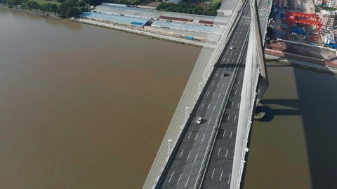 The drone smoothly flies around a large cable-stayed bridge on which cars drive. Video stock 113665915