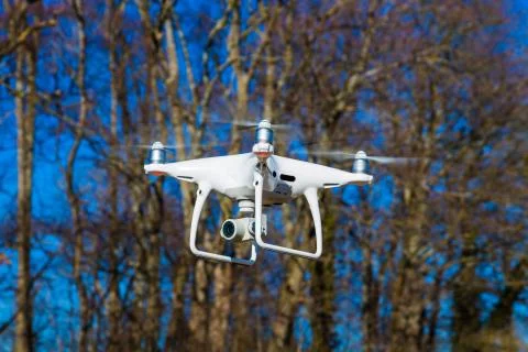 Drone soars in front of trees Stock Photos