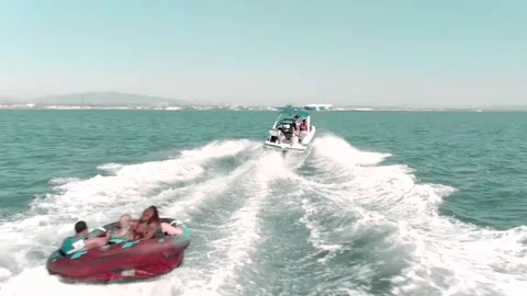 Drone of speed boat pulling people in water tube Stock Footage 136142610