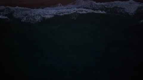Drone sunrise view of dark ocean waves rolling toward shore Stock Footage 321899487
