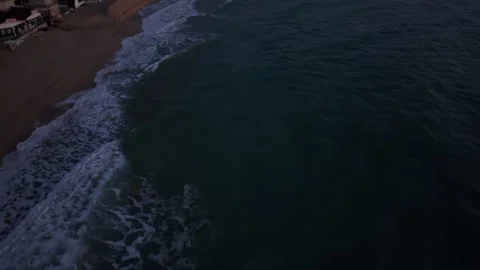 Drone sunrise view of waves rolling onto a quiet sandy beach Stock Footage 321899104