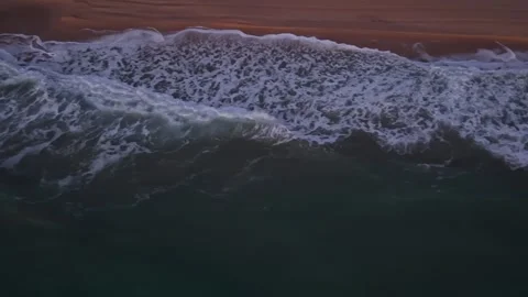 Drone sunrise view of waves rolling onto sandy coastal shoreline Stock Footage 321899164