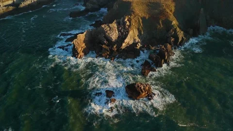 Drone Sunset Left Circle Over Green Blue Waves Focusing On Cliff And Stones Stock Footage 321189304