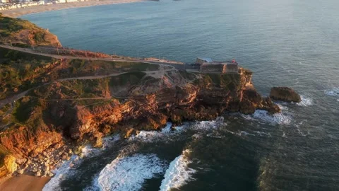 Drone sunset over Nazaré Lighthouse and Atlantic waves in Portugal. Stock Footage 329118697