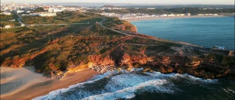 Drone sunset over Nazaré Lighthouse and Atlantic waves in Portugal. Stock Footage 329118804